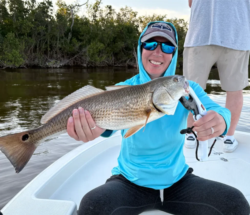 Woman holding a redfish caught while fishing the mangroves of Charlotte Harbor